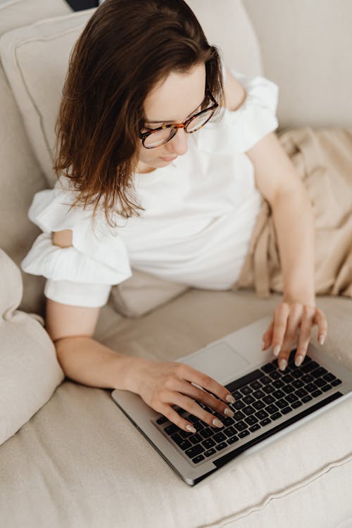 A Woman Typing on Laptop while on the Couch