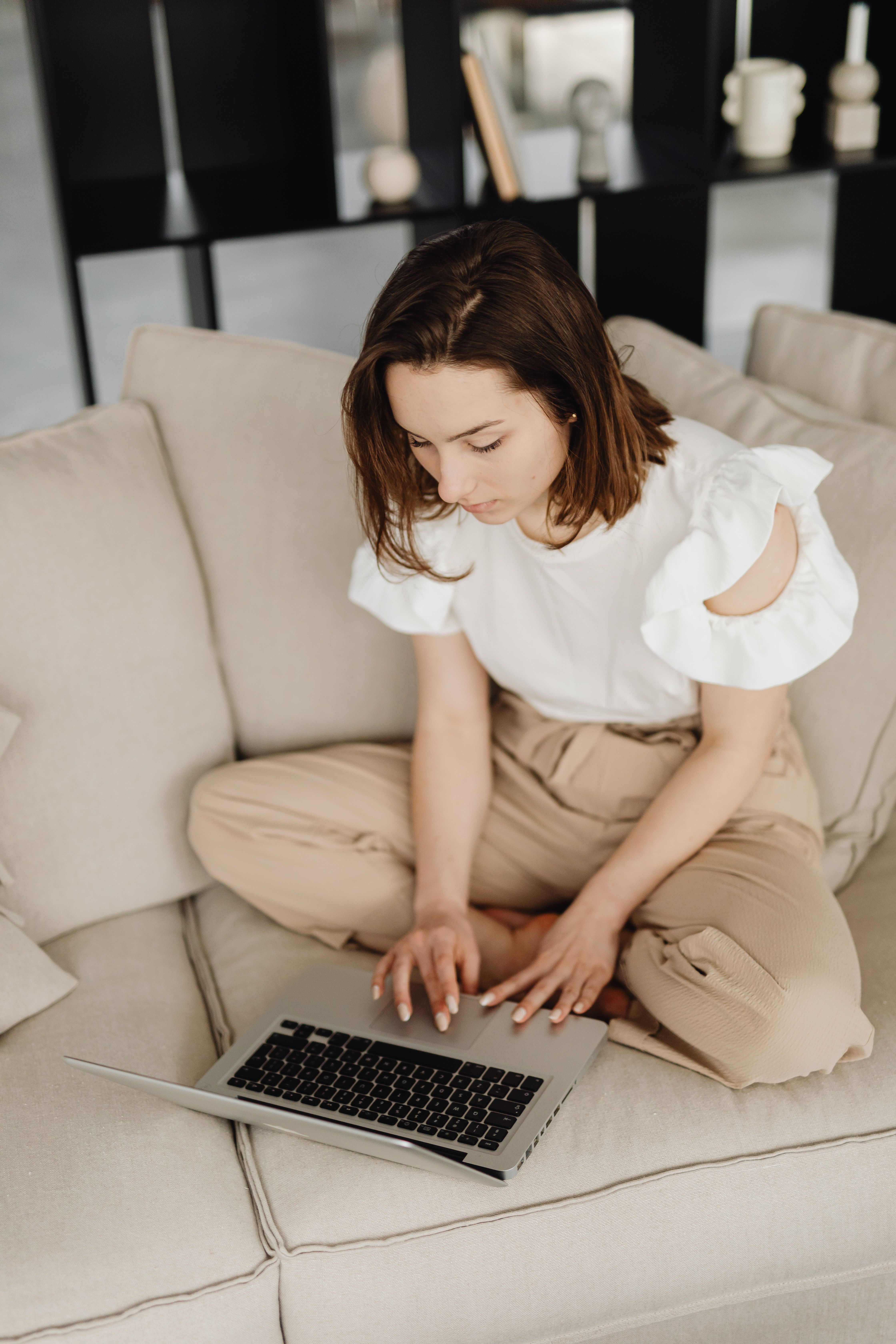 Caucasian woman focused on work at home using a laptop on her sofa.