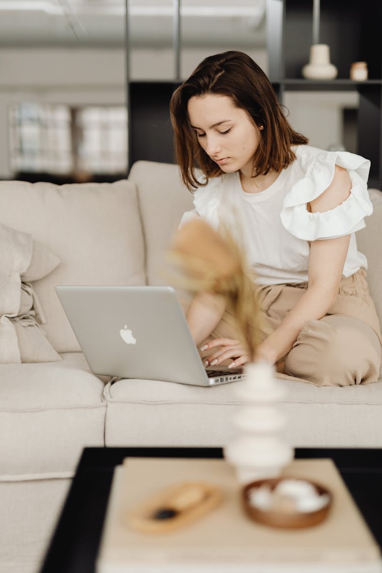 A Woman On The Couch Typing On MacBook