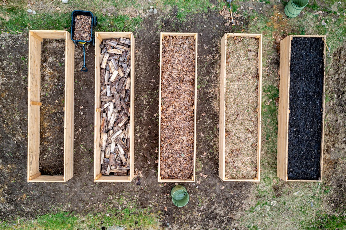 Free Top view of wooden boxes with piles of firewood wood chips sawdust and coal placed on ground in agricultural plantation Stock Photo