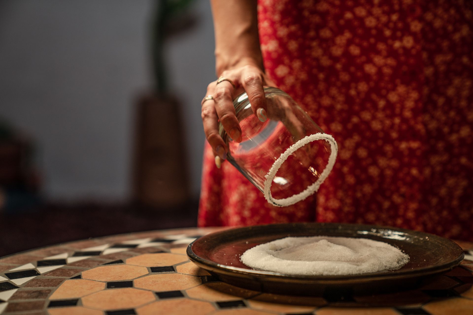 A person salts the rim of a glass above a decorative table. Elegant culinary ambiance.