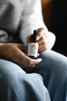 A close-up of hands holding a CBD oil bottle, highlighting the product label and design.