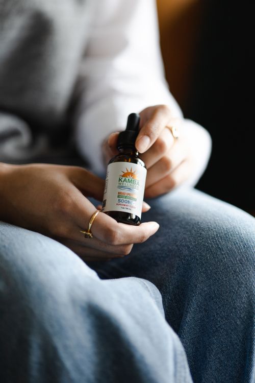 Free A close-up of hands holding a CBD oil bottle, highlighting the product label and design. Stock Photo