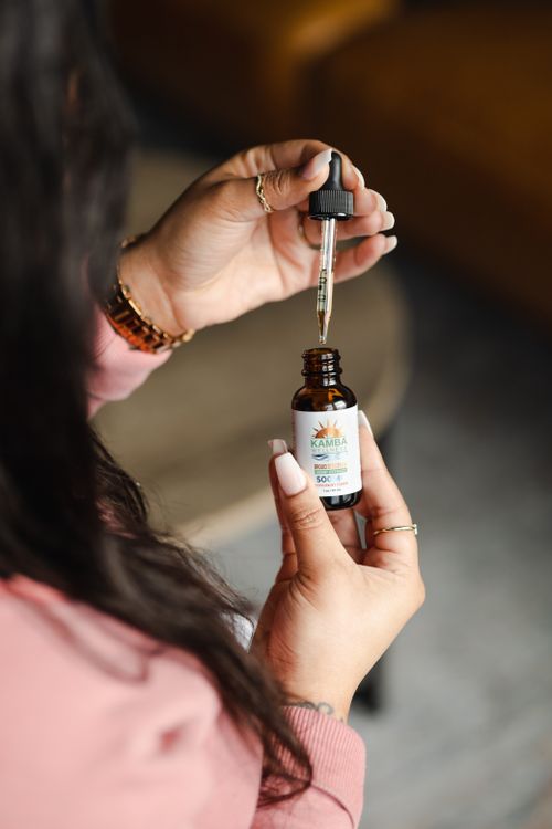 Free A person holding and using a CBD oil dropper bottle, focusing on natural wellness. Stock Photo