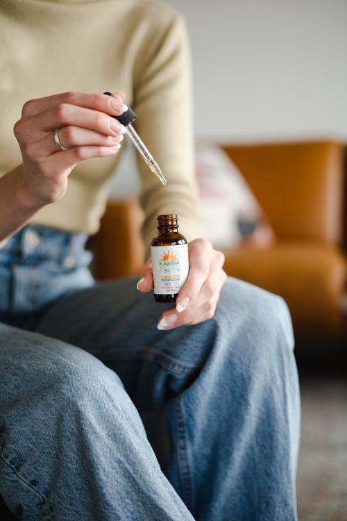 Free A woman carefully holds a CBD oil dropper bottle, representing natural health and skincare. Stock Photo
