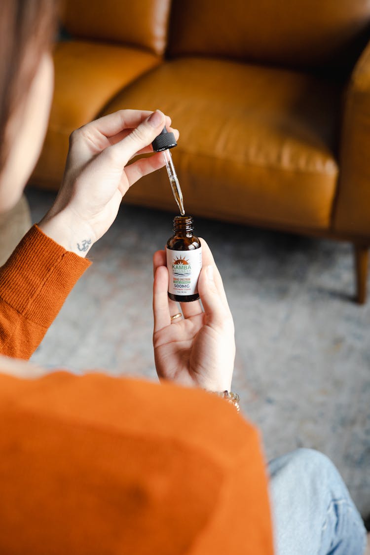 A Woman Using Essential Oil Contained In Bottle Dropper