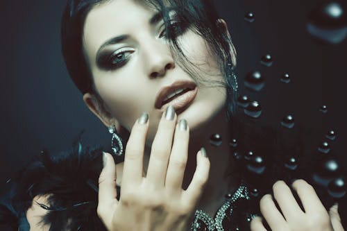 Mysterious woman with dark makeup looking at camera against black background