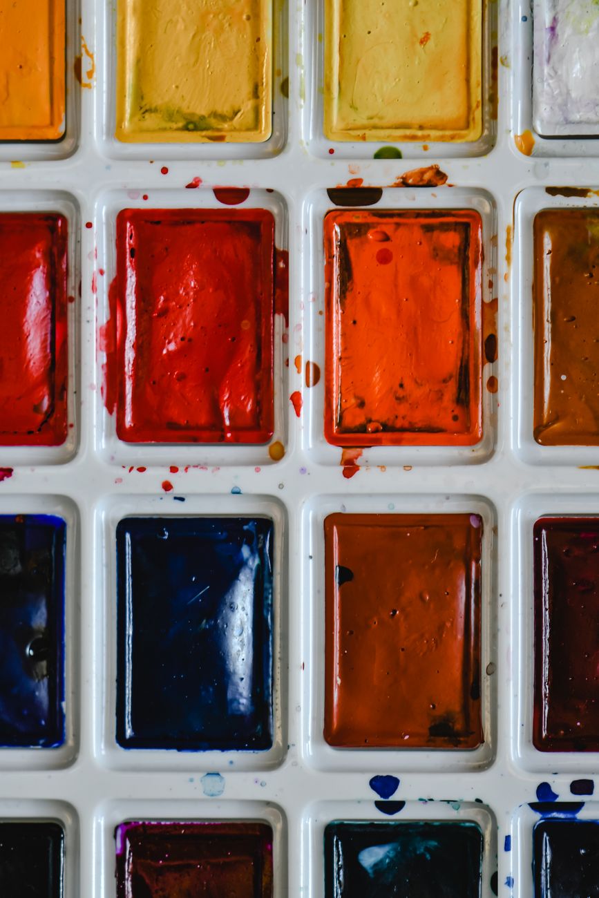 Close-up of a vibrant watercolor palette showcasing a variety of bright and warm colors.. close, vibrant, watercolor