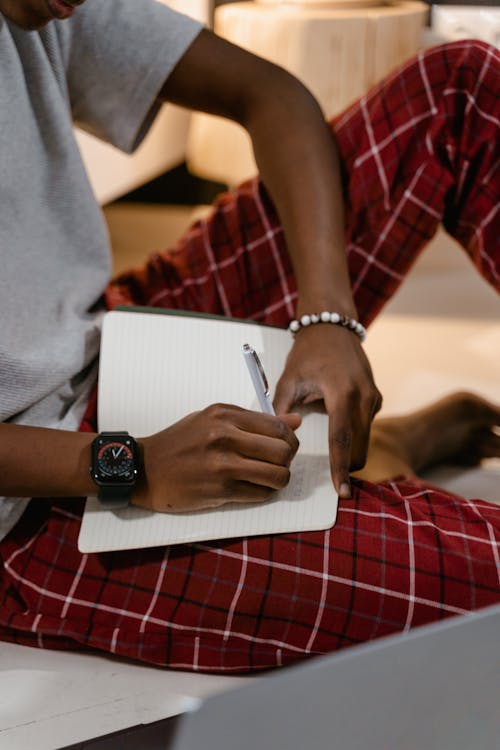 A Person Writing on a Notebook