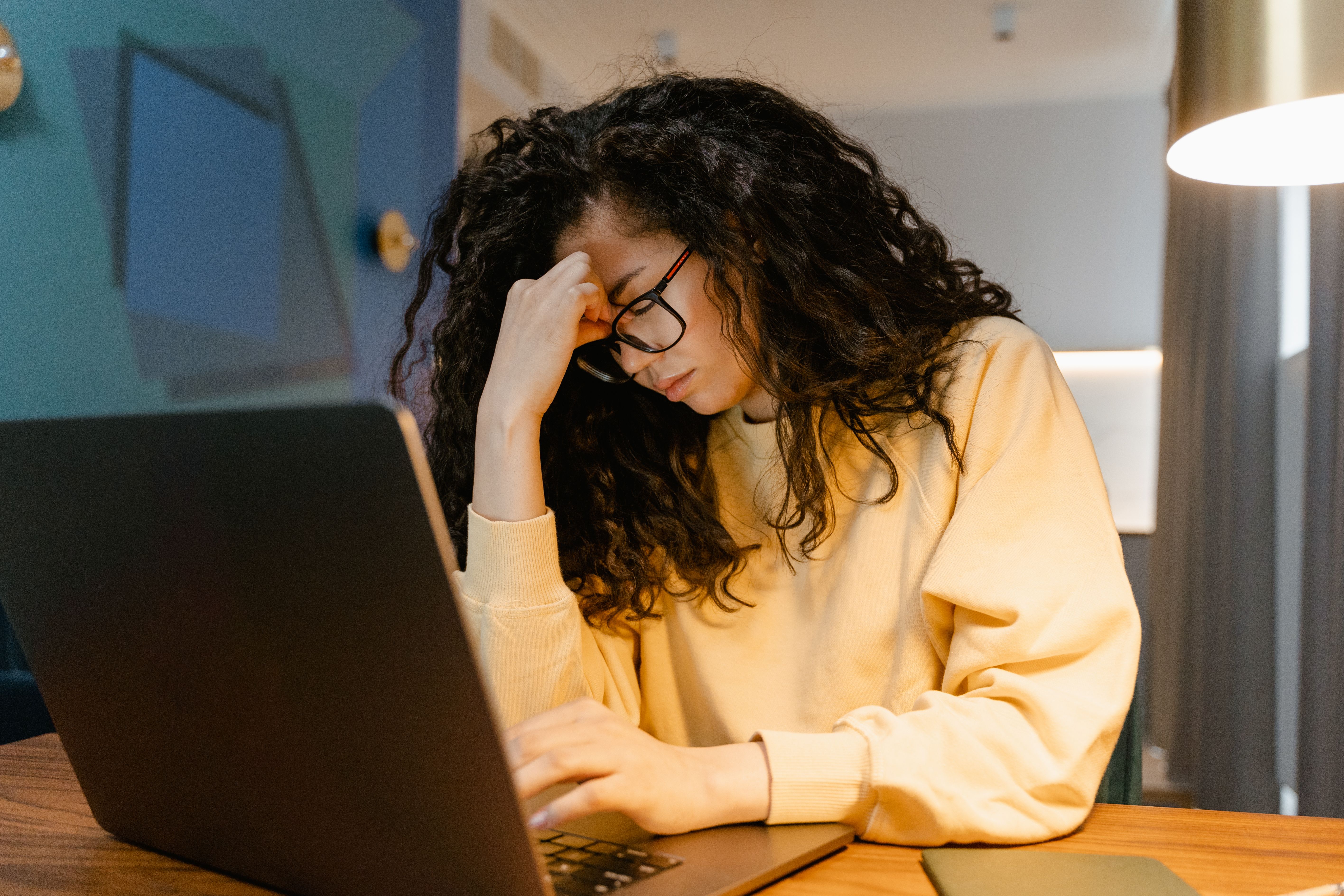 Woman feeling stressed while working on a laptop at a desk