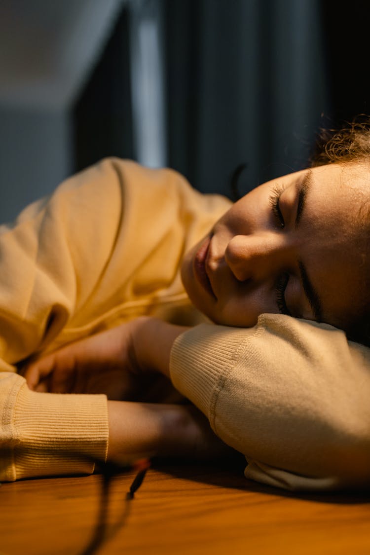 A Woman Sleeping On A Wooden Desk