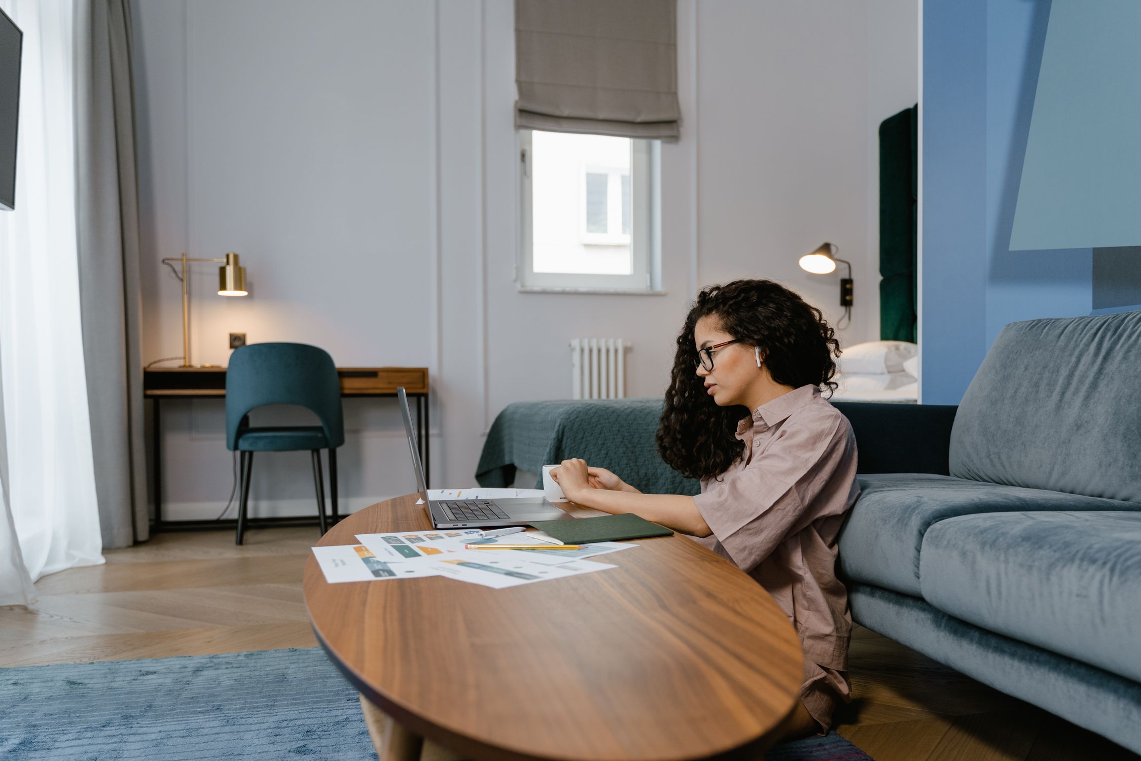 A woman working from home, focused on her laptop in a stylish living room setting.