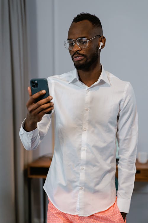 Free Bearded Man in White Long Sleeve Shirt Holding a Cellphone Stock Photo