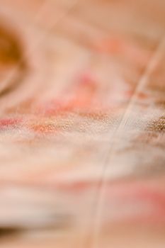 Close-up of abstract fabric texture with warm color tones and blurred surface.