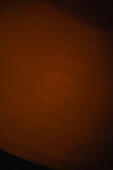 A close-up view of a spinning vinyl record with a warm brown tone, emphasizing texture.