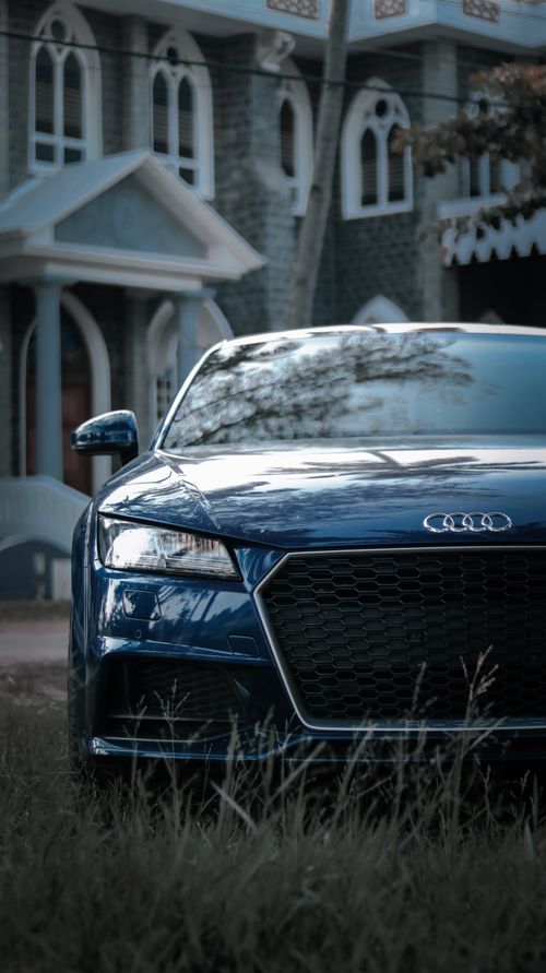 Free Close-up of a glossy luxury sports car parked in front of an elegant residence, showcasing sleek design and modern architecture. Stock Photo