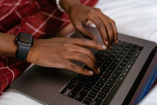 Person typing on keyboard with smartwatch on wrist, focused and productive.