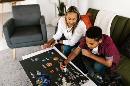 Free A mother and son collaboratively working on a solar system project indoors. Stock Photo