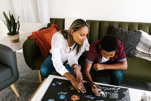 Free Mother and son bond over a creative drawing session in a cozy living room setting. Stock Photo