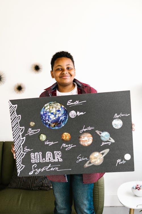 A Kid Holding a Board while Smiling at the Camera