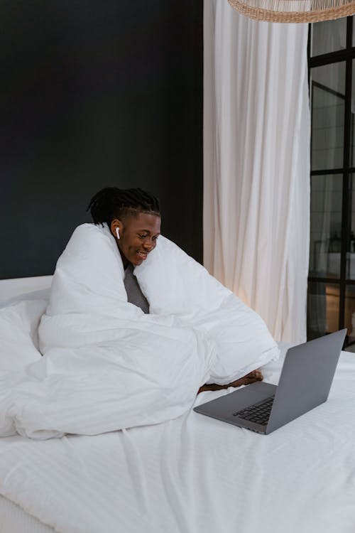 Man Sitting on Bed While Looking at the Screen of a Computer