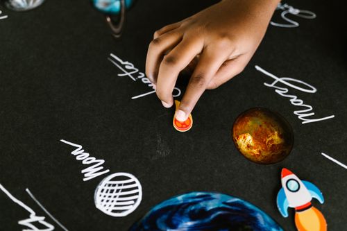 Free Close-up of a child's hand interacting with a solar system model for a school project. Stock Photo