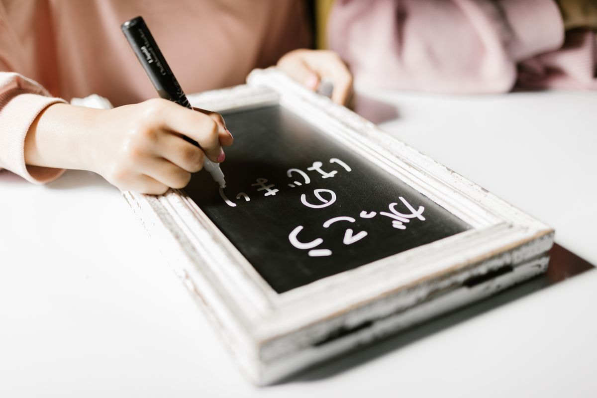 Child writing on small chalkboard exploring creativity and education