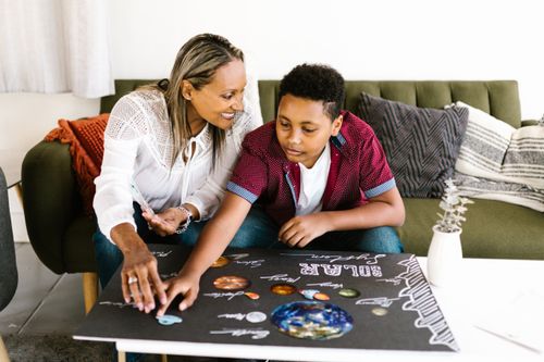 Free A mother and son collaborating on a solar system project in a cozy living room setting. Stock Photo
