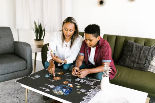 Free A mother and son collaborate on a solar system craft project at home. Stock Photo