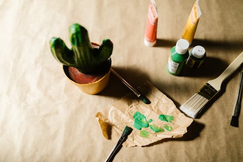 Paints and Paintbrushes next to a Craft Project 