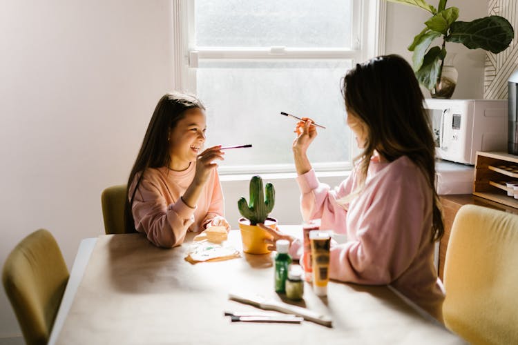 Mother And Daughter Painting On The Table