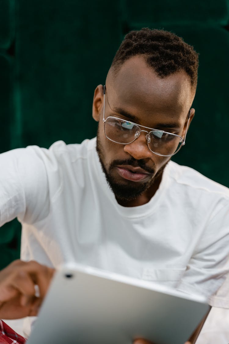 Close-up Photo Of Man With Eyeglasses Using An Ipad 