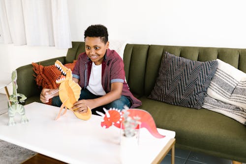 Free Boy Sitting on Sofa While Playing with a Toy Stock Photo