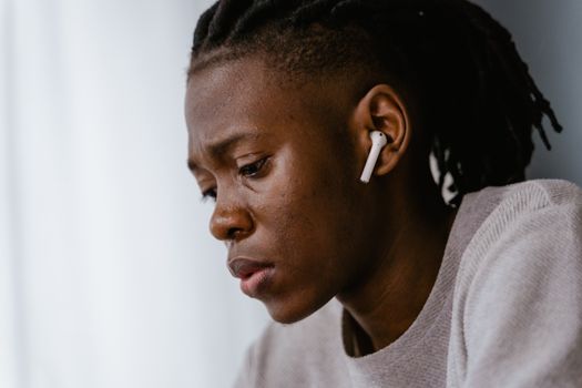 Side profile of a focused individual wearing wireless earphones, conveying introspection.