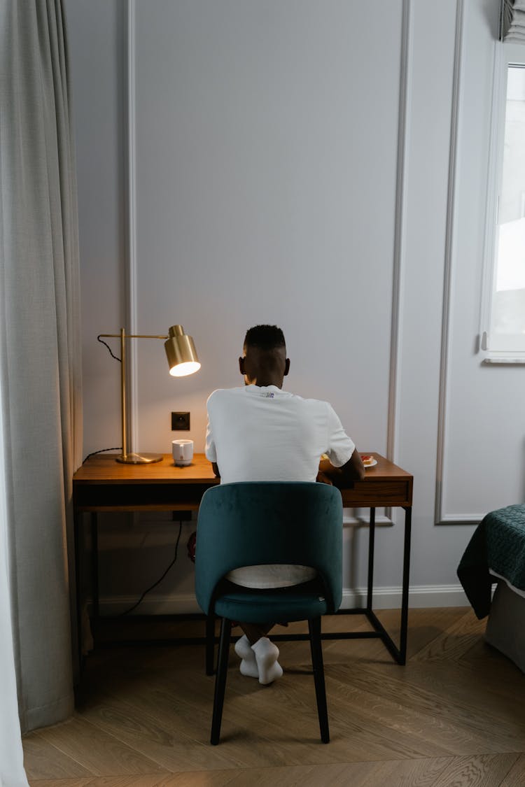 Back View Of A Man Sitting At His Desk