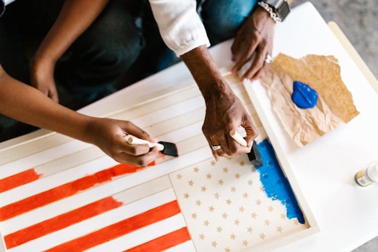 A Parent And A Child Painting An American Flag