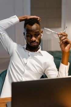 Focused man working remotely from home, contemplating while on laptop.