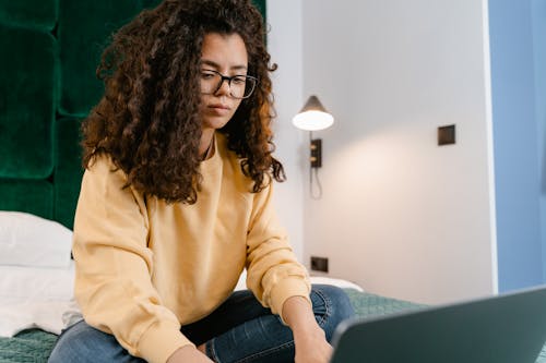 Free Woman with Curly Hair Using a Laptop Stock Photo