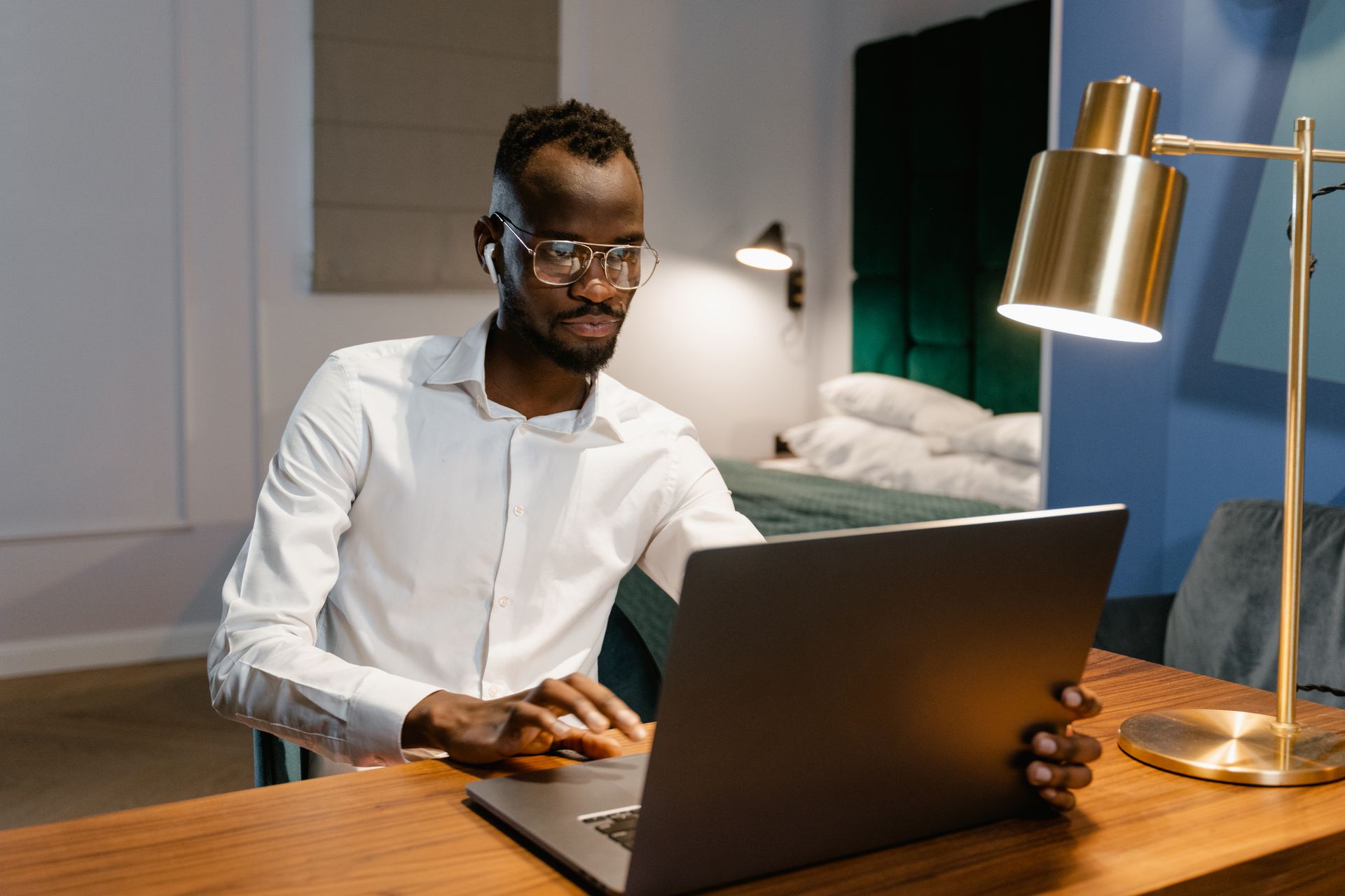 Man wearing eyeglasses working on laptop in a cozy home office setting.