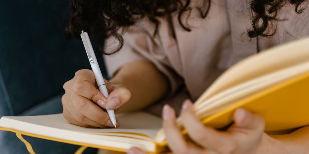 Woman in white shirt writing on paper at a desk