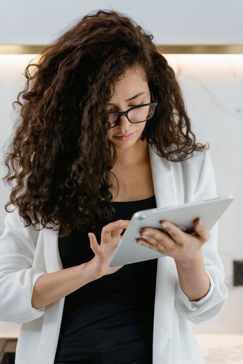Free Focused young woman using a tablet in a modern indoor setting. Stock Photo