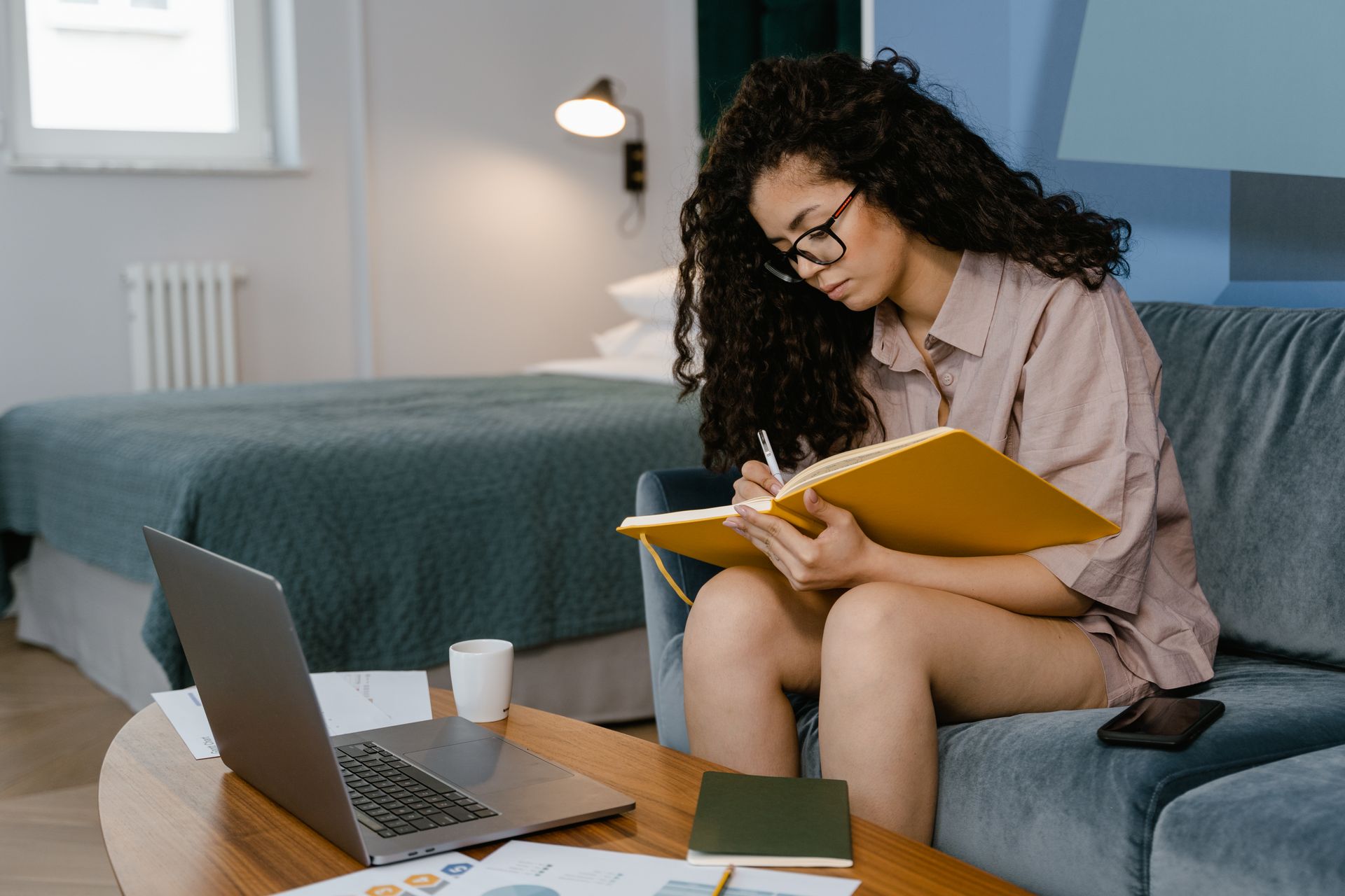 Woman journaling in a cozy home setting, reflecting on her goals