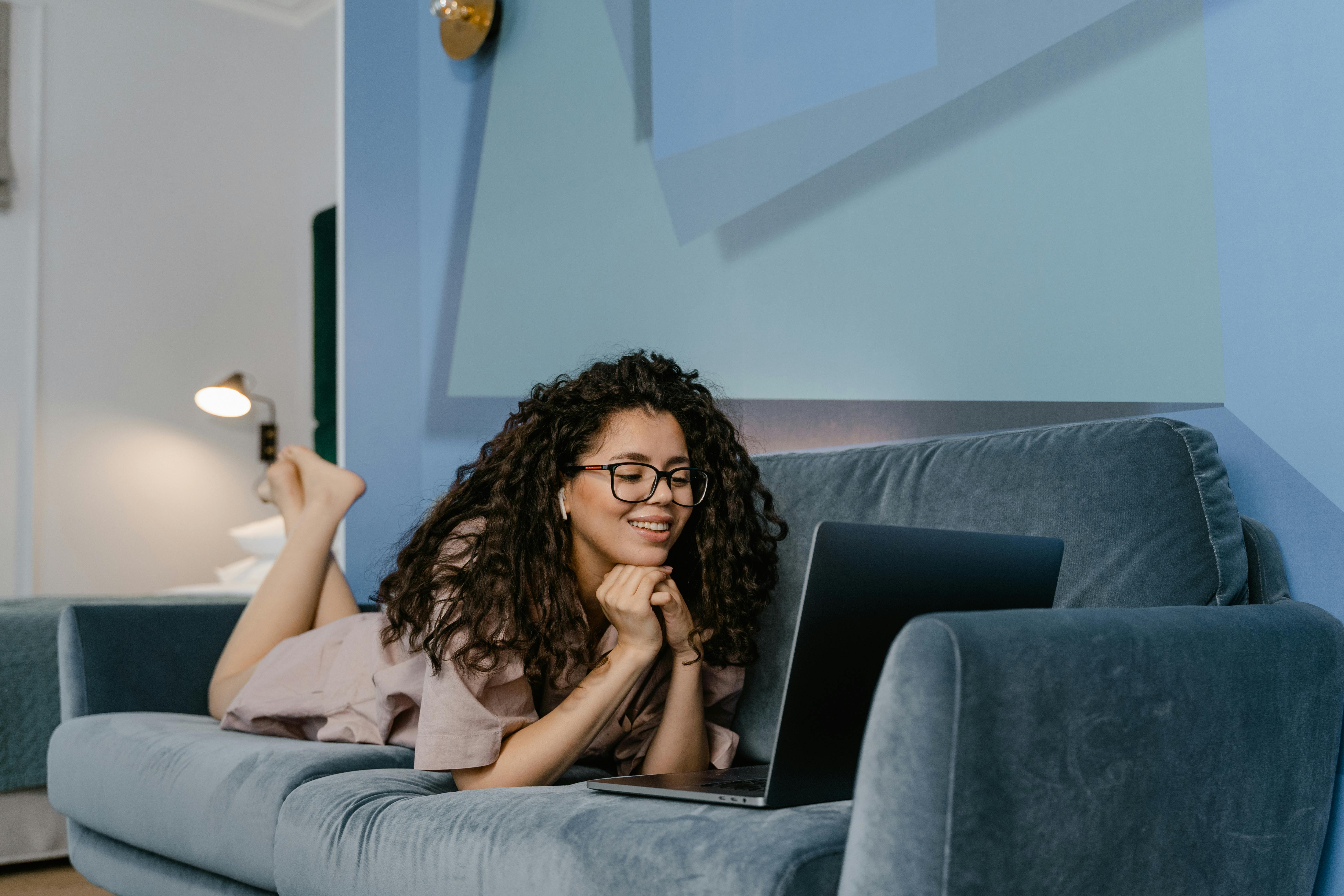 a young woman video calling with a laptop on a couch