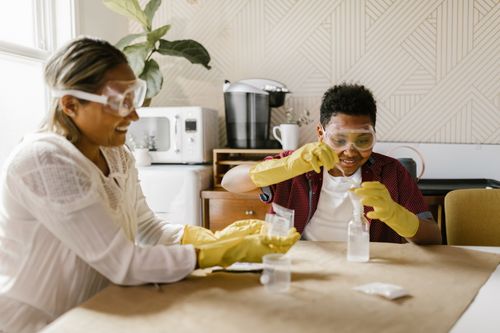 Free A woman and boy conducting a fun science experiment indoors with safety goggles and gloves. Stock Photo