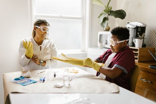 Free Mother and son engaged in a fun, indoor science experiment using protective goggles and gloves. Stock Photo