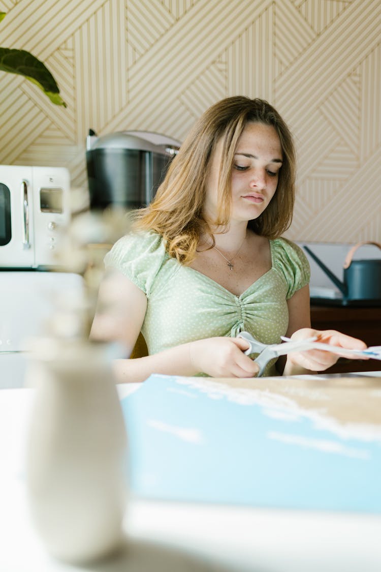 A Woman Cutting Paper At The Table