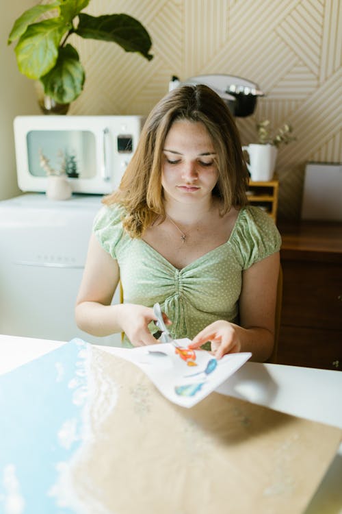 A Girl Cutting Pictures on a White Paper