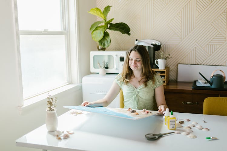 A Girl Holding A School Project At A Table