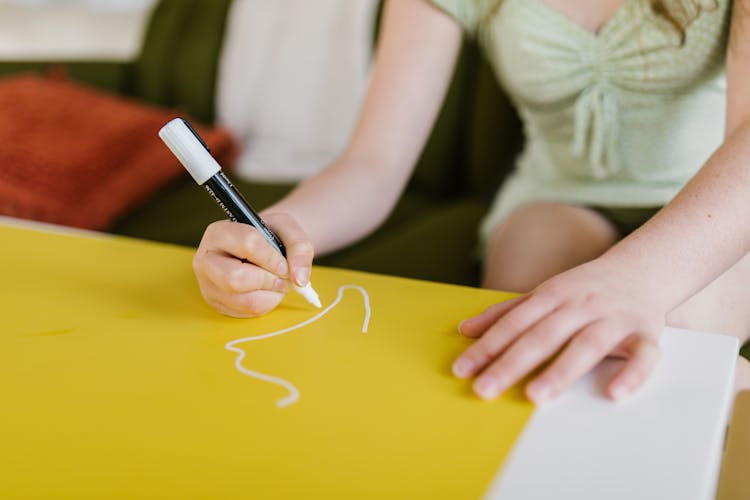 A Girl Drawing On A Yellow Paper