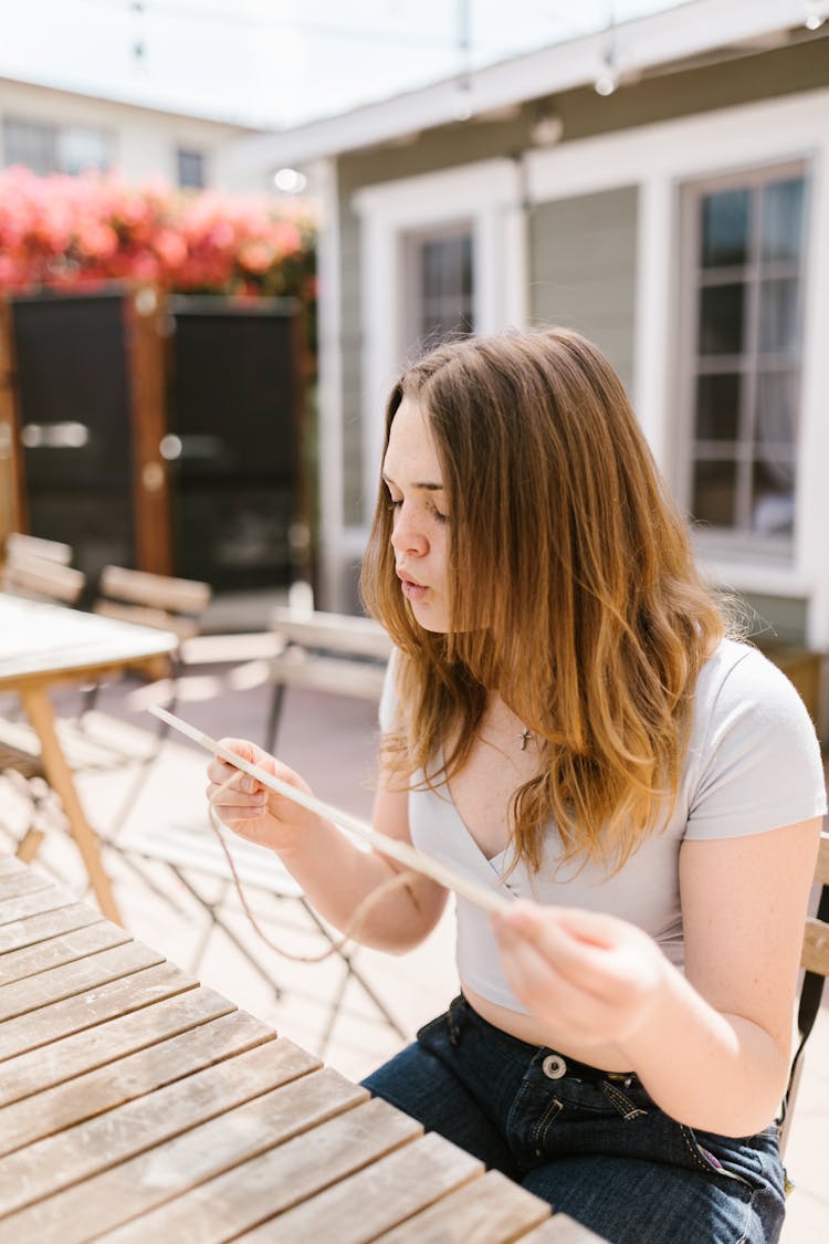 A Girl Blowing On An Object With Sting